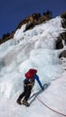 Male ice climber in a blue jacket on a gorgeous frozen waterfall climbing in the Alps in deep winter Royalty Free Stock Photo
