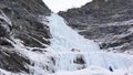 Male ice climber stands at the headwall of a long and steep waterfall in the Alps