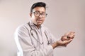 Male indian doctor in white coat and stethoscope with medicine pills tablets capsules in hand Royalty Free Stock Photo