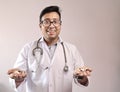 Male indian doctor in white coat and stethoscope with medicine pills tablets capsules in hand Royalty Free Stock Photo