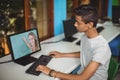 Male indian student having a video call with female teacher on computer at school Royalty Free Stock Photo