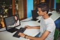 Male indian student having a video call with female teacher on computer at school Royalty Free Stock Photo