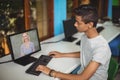 Male indian student having a video call with female teacher on computer at school Royalty Free Stock Photo