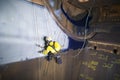 Male industrial rope access technician painter working at height hanging on twin ropes Royalty Free Stock Photo