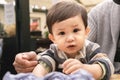 A male infant looking at camera staring with big brown eyes sitting on his unrecognizable dad\'s legs in a beer garden Royalty Free Stock Photo