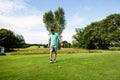Male amateur golfer wearing glove, holding club and placing ball on tee box at parkland fairway Royalty Free Stock Photo