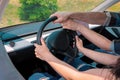 Woman learning to drive car and male instructor helping her while holding steering wheel. Cropped. Test drive