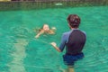 Male instructor swimming for children teaches a happy boy to swim in the pool Royalty Free Stock Photo