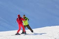 Male instructor teaches skiing to a young woman on a sunny day on snowy slope background