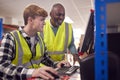 Male Intern With Supervisor Working In Busy Modern Warehouse On Computer Terminal Royalty Free Stock Photo