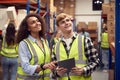 Male Intern With Team Leader Looking At Digital Tablet Inside Busy Warehouse Facility Royalty Free Stock Photo