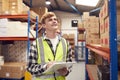 Male Intern Working Inside Warehouse Checking Stock On Shelves Using Clipboard Royalty Free Stock Photo