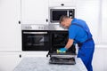 Male Janitor Cleaning Oven In Kitchen