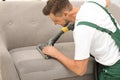 Male janitor removing dirt from sofa