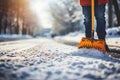 A male janitor shovels snow from the road