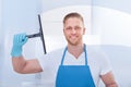 Male janitor using a squeegee to clean a window