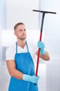 Male janitor using a squeegee to clean a window