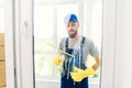 Male janitor using a squeegee to clean a window in an office wearing an apron and gloves as he works Royalty Free Stock Photo