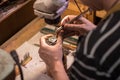 A male jeweler fixes precious stones on a silver pendant.