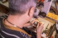 A male jeweler fixes precious stones on a silver pendant.