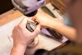 A male jeweler fixes precious stones on a silver pendant.