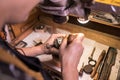 A male jeweler fixes precious stones on a silver pendant.