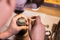 A male jeweler fixes precious stones on a silver pendant.