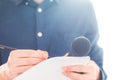 Male journalist at news conference, holding microphone and taking notes Royalty Free Stock Photo