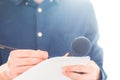 Male journalist at news conference, holding microphone and taking notes Royalty Free Stock Photo