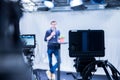 Journalist in a television studio is talking into a microphone, blurry film cameras Royalty Free Stock Photo