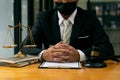A male judge in the courtroom on a wooden table and a counselor or lawyer working in the office. A law with golden hammers and sca Royalty Free Stock Photo