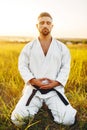 Male karate fighter sitting on the ground in field