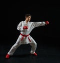 Male karate fighter in white kimono and red gloves