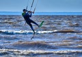 A male kiteboarder jumps above the surface of the water of a large river.