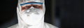 Male lab worker in protective respirator and white coverall, smart scientist