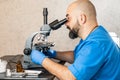 Male laboratory assistant examining biomaterial samples in a microscope Royalty Free Stock Photo