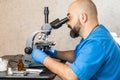 Male laboratory assistant examining biomaterial samples in a microscope Royalty Free Stock Photo