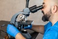 Male laboratory assistant examining biomaterial samples in a microscope Royalty Free Stock Photo