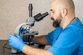 Male laboratory assistant examining biomaterial samples in a microscope Royalty Free Stock Photo