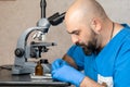 Male laboratory assistant examining biomaterial samples in a microscope Royalty Free Stock Photo