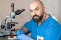 Male laboratory assistant examining biomaterial samples in a microscope Royalty Free Stock Photo