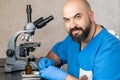 Male laboratory assistant examining biomaterial samples in a microscope Royalty Free Stock Photo