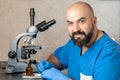 Male laboratory assistant examining biomaterial samples in a microscope Royalty Free Stock Photo