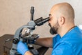 Male laboratory assistant examining biomaterial samples in a microscope Royalty Free Stock Photo