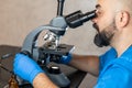 Male laboratory assistant examining biomaterial samples in a microscope Royalty Free Stock Photo