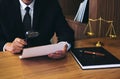 Male lawyer reading legal contract agreement and examining documents with magnifying glass in courtroom