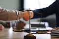 Male lawyer shaking hands with client, focus on scales of justice Royalty Free Stock Photo