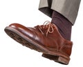 Male left foot in brown shoe takes a step