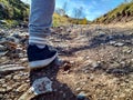 Male leg closeup wearing trainers while hiking, jogging, walking in the nature and going forward for better lifestyle on a rocky