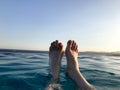 Male legs, feet with fingers spread out in a beautiful blue wet azure natural clear water against a blue sky and horizon line in a Royalty Free Stock Photo